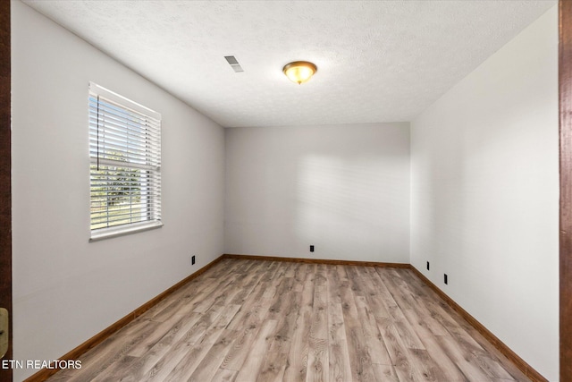 spare room with a textured ceiling and light wood-type flooring