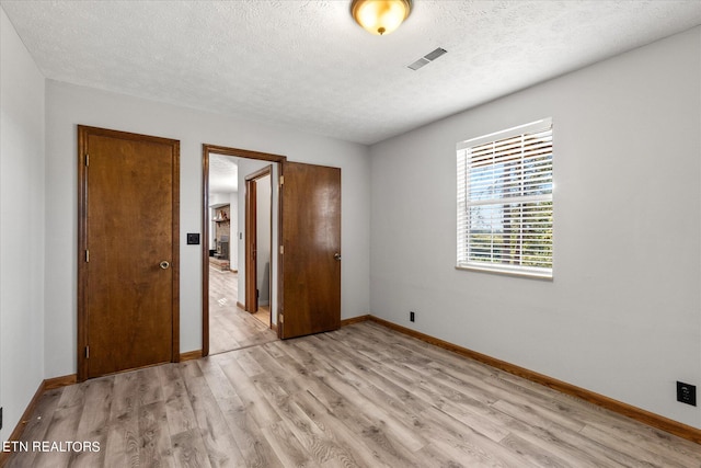 unfurnished bedroom featuring a closet, a textured ceiling, and light hardwood / wood-style floors