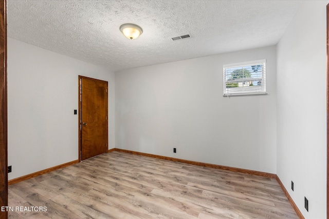 unfurnished room with a textured ceiling and light hardwood / wood-style floors