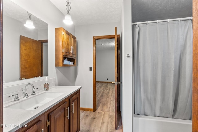 bathroom with vanity, a textured ceiling, hardwood / wood-style flooring, and shower / tub combo