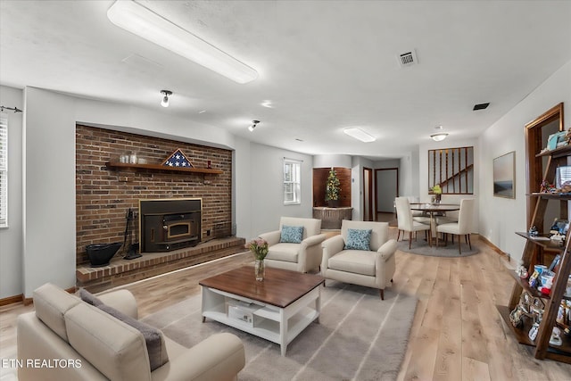 living room featuring a fireplace, a wood stove, and light hardwood / wood-style flooring