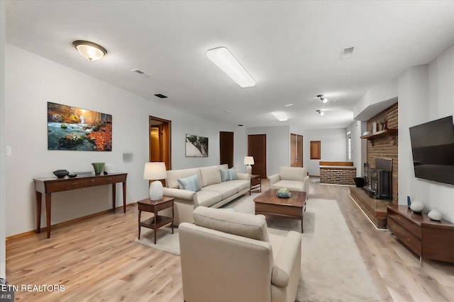 living room featuring light hardwood / wood-style flooring and a brick fireplace