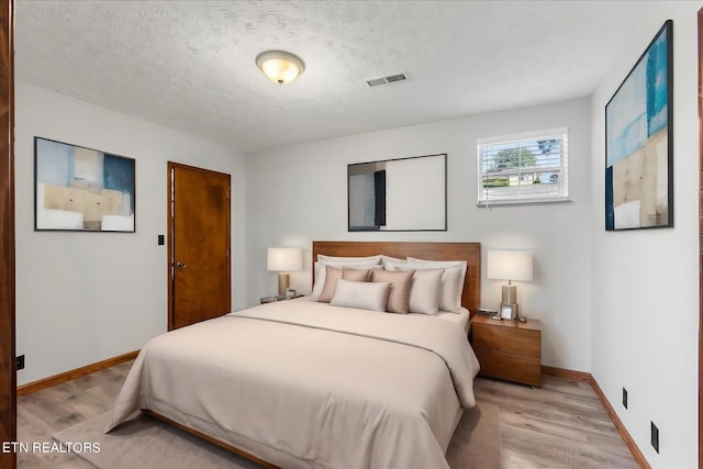 bedroom featuring light hardwood / wood-style floors and a textured ceiling