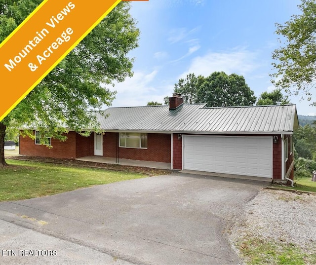 320 Redbird Cir, Cumberland Gap, TN 37724 - view of front of house featuring an attached garage, driveway, a metal roof, a chimney, and a front lawn