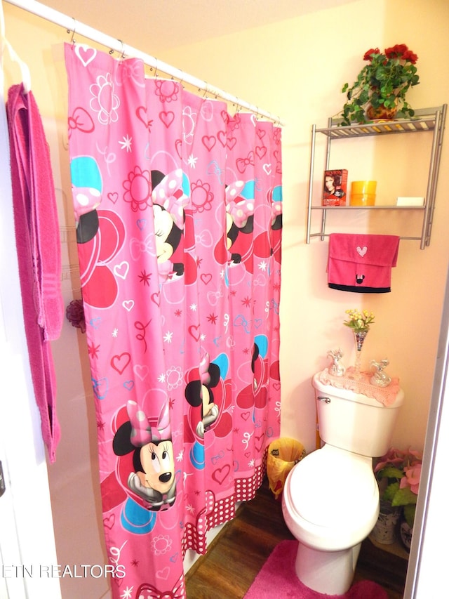 bathroom featuring toilet, a shower with curtain, and wood-type flooring