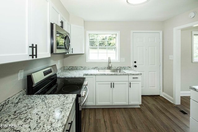 kitchen with dark hardwood / wood-style floors, light stone countertops, stainless steel appliances, sink, and white cabinets