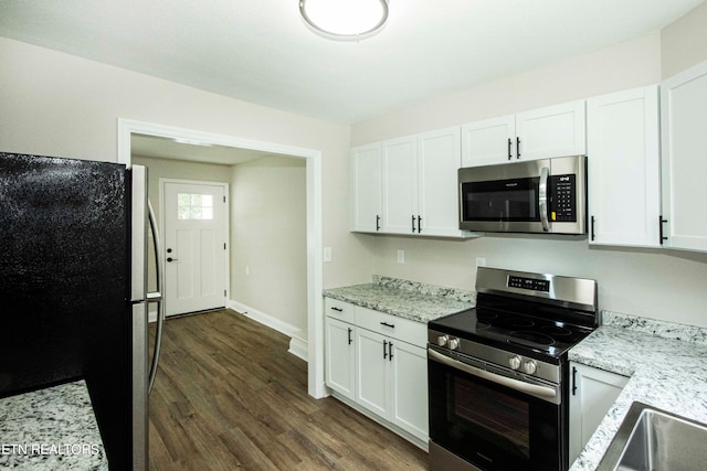 kitchen with dark wood-type flooring, white cabinets, light stone countertops, and stainless steel appliances