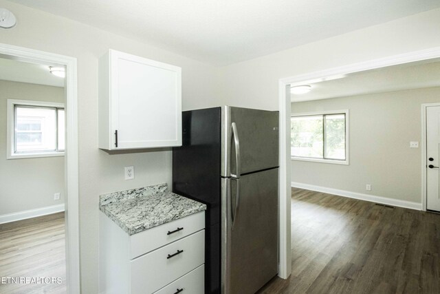 kitchen with stainless steel fridge, white cabinetry, plenty of natural light, and light hardwood / wood-style floors