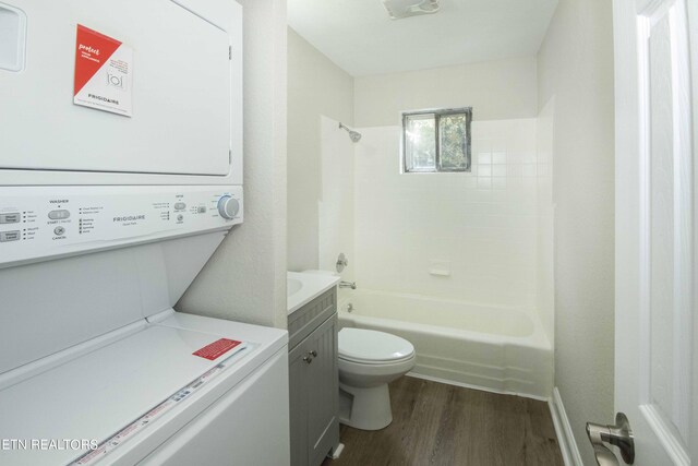 full bathroom with vanity, stacked washer and dryer, wood-type flooring, toilet, and tiled shower / bath