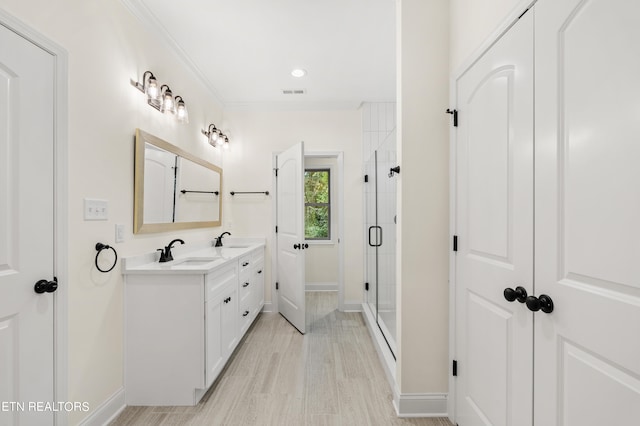 bathroom with crown molding, hardwood / wood-style flooring, vanity, and a shower with door