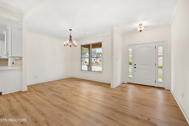 entrance foyer with light hardwood / wood-style floors, ornamental molding, and a chandelier