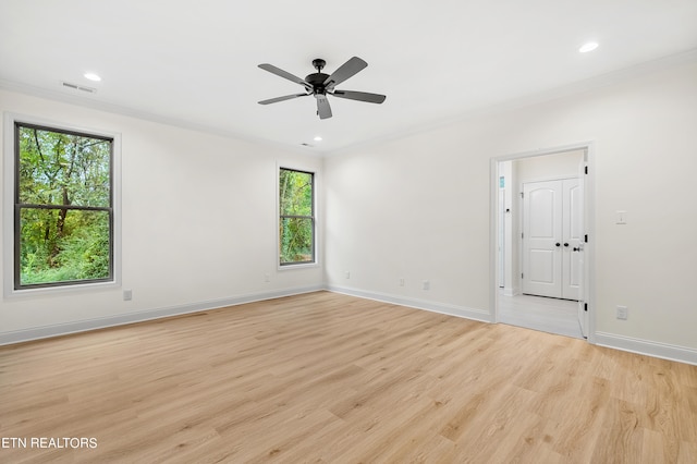 spare room with light wood-type flooring, ornamental molding, ceiling fan, and a wealth of natural light