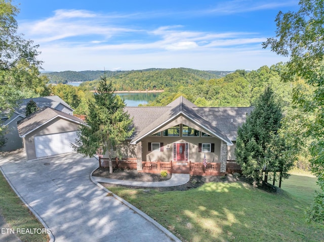 view of front of house featuring a garage, a porch, a front lawn, and a water view