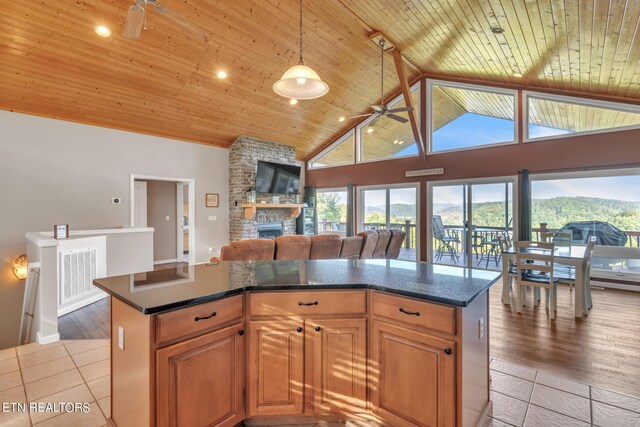 kitchen featuring light wood-type flooring, plenty of natural light, a fireplace, ceiling fan, and wooden ceiling