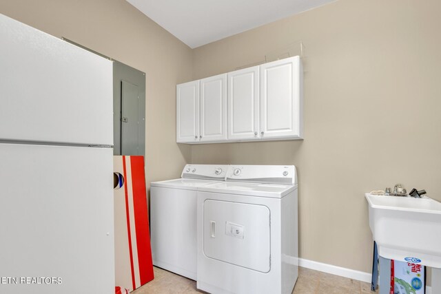 washroom with cabinets, sink, light tile patterned floors, and washing machine and dryer