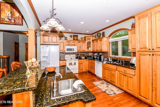 kitchen with light wood-type flooring, white appliances, decorative columns, an island with sink, and sink