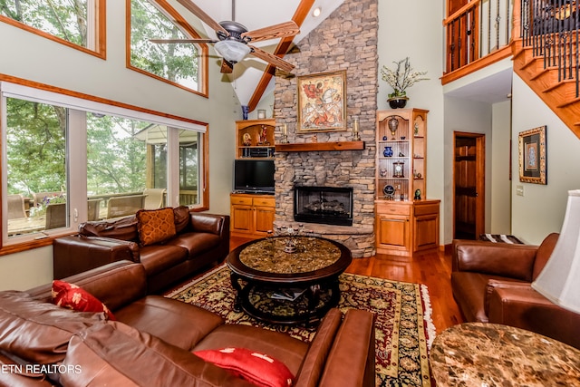 living room with hardwood / wood-style floors, high vaulted ceiling, a fireplace, and ceiling fan