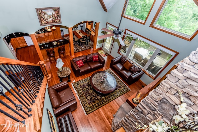 living room with hardwood / wood-style flooring, ceiling fan, and a high ceiling