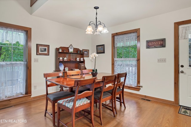 dining area with light wood-type flooring and an inviting chandelier