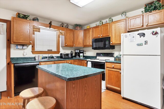 kitchen with light hardwood / wood-style floors, sink, black appliances, a breakfast bar area, and a kitchen island