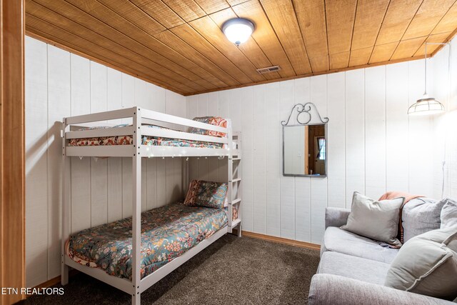 bedroom with wooden walls, dark colored carpet, and wooden ceiling