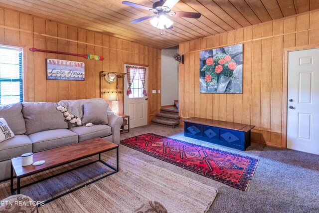 living room with carpet flooring, wood ceiling, wood walls, and ceiling fan