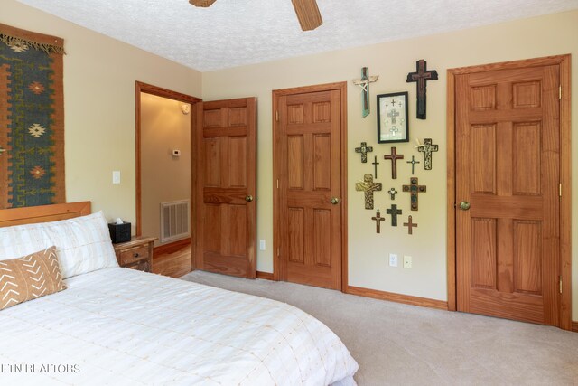 carpeted bedroom featuring ceiling fan and a textured ceiling