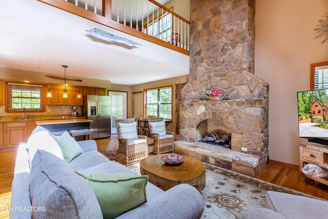 living room with a high ceiling, wood-type flooring, a fireplace, and sink