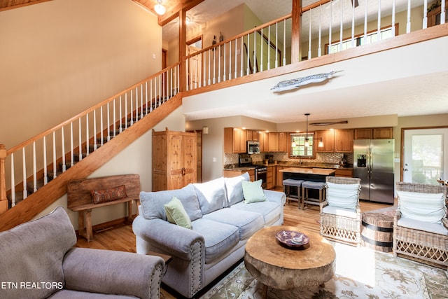 living room with light hardwood / wood-style floors, a high ceiling, and sink