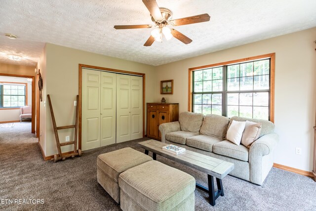 living room featuring ceiling fan, carpet floors, and a textured ceiling