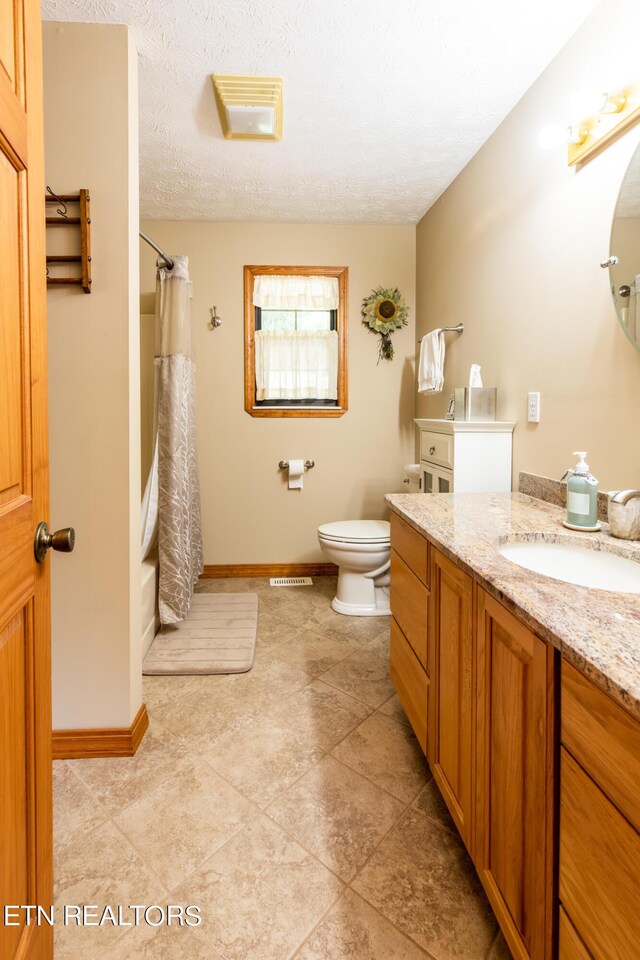 bathroom featuring curtained shower, vanity, a textured ceiling, tile patterned flooring, and toilet