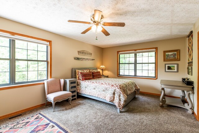 carpeted bedroom with ceiling fan and a textured ceiling