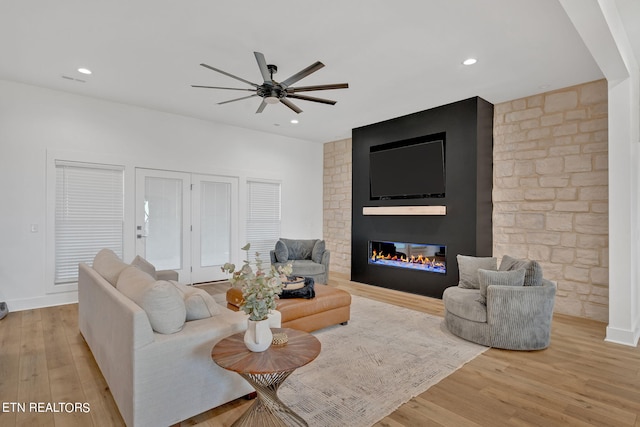 living room featuring a fireplace, ceiling fan, and light hardwood / wood-style flooring