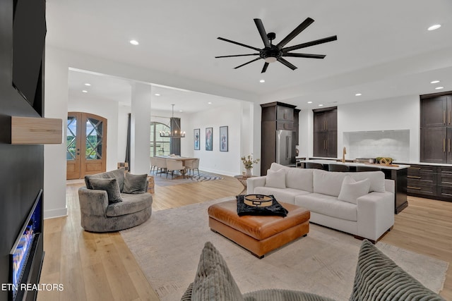 living room with french doors, light hardwood / wood-style floors, and ceiling fan with notable chandelier