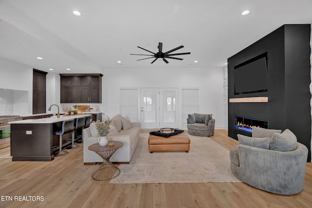 living room with a fireplace, light hardwood / wood-style flooring, and ceiling fan