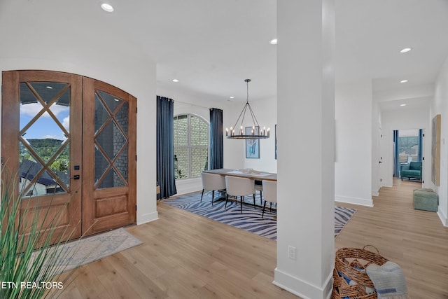 entryway featuring light hardwood / wood-style floors, french doors, and an inviting chandelier