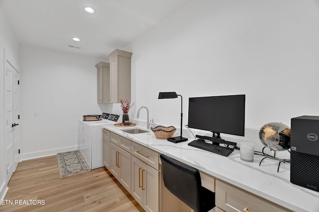 kitchen featuring light stone countertops, sink, built in desk, washing machine and clothes dryer, and light hardwood / wood-style floors