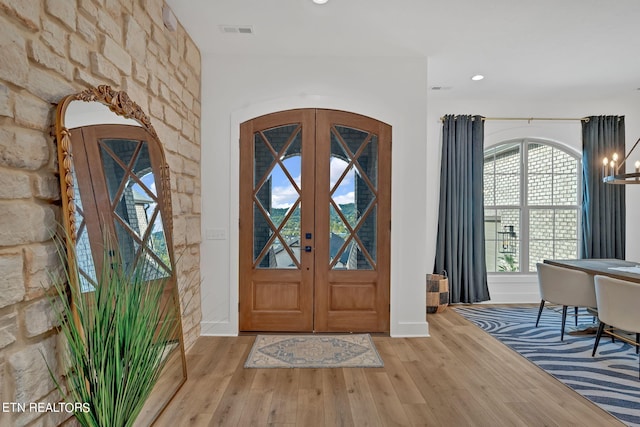 foyer entrance with a chandelier, light wood-type flooring, and french doors