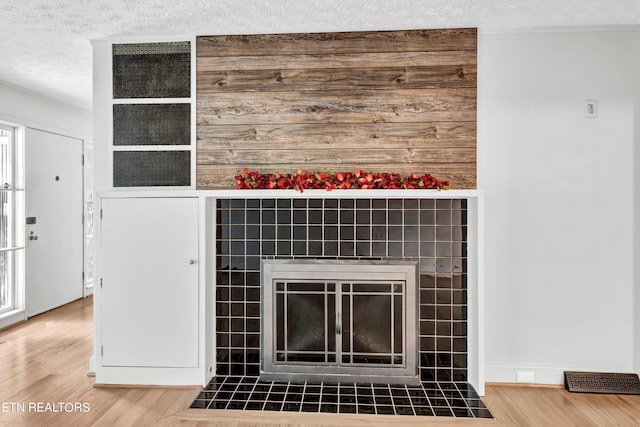 details with hardwood / wood-style floors, a textured ceiling, and a tile fireplace