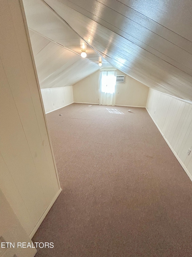 additional living space with lofted ceiling, carpet, and wooden walls