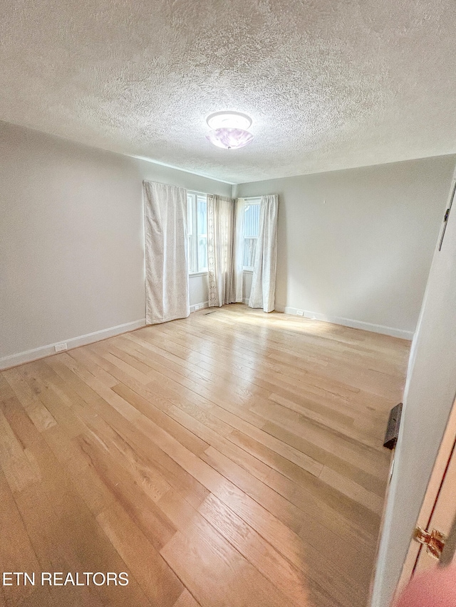 empty room with a textured ceiling and light wood-type flooring