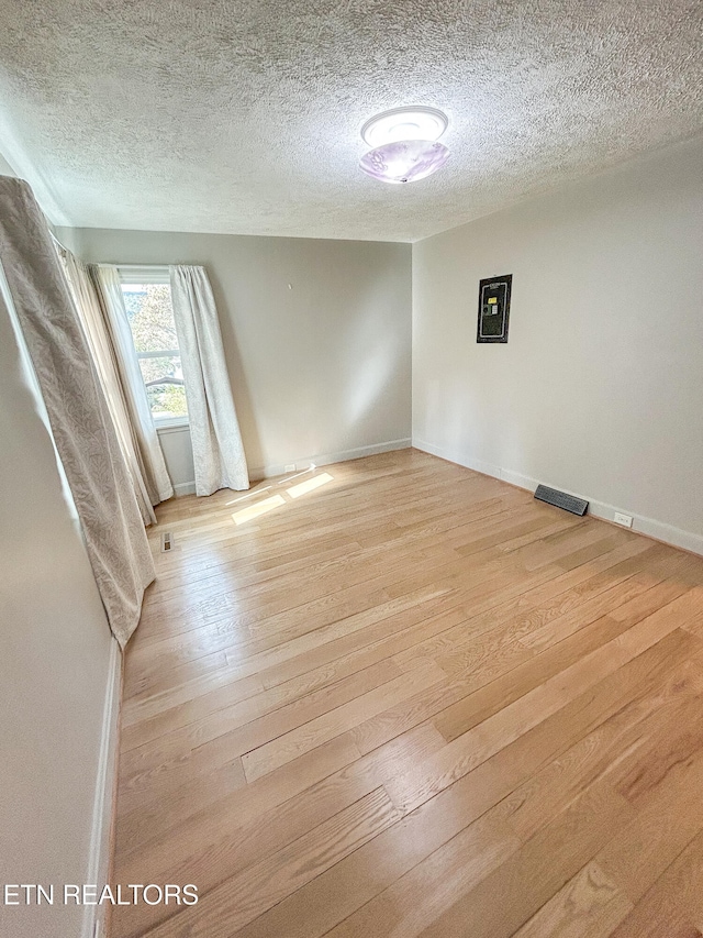 spare room featuring a textured ceiling and light wood-type flooring