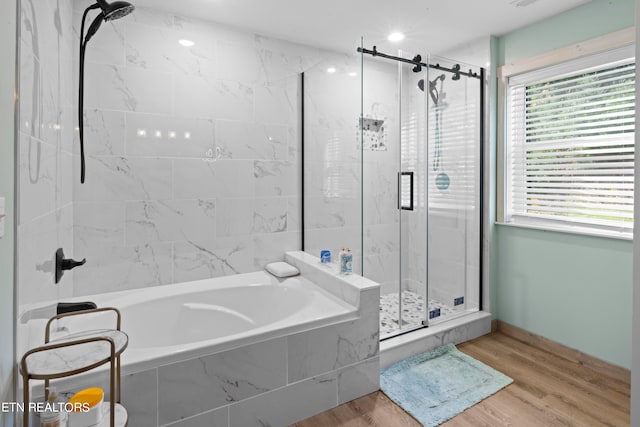 bathroom with shower with separate bathtub and wood-type flooring