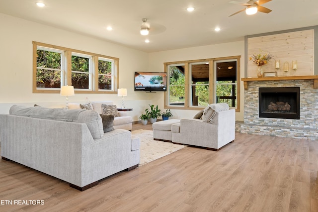 living room featuring a stone fireplace, ceiling fan, and hardwood / wood-style flooring