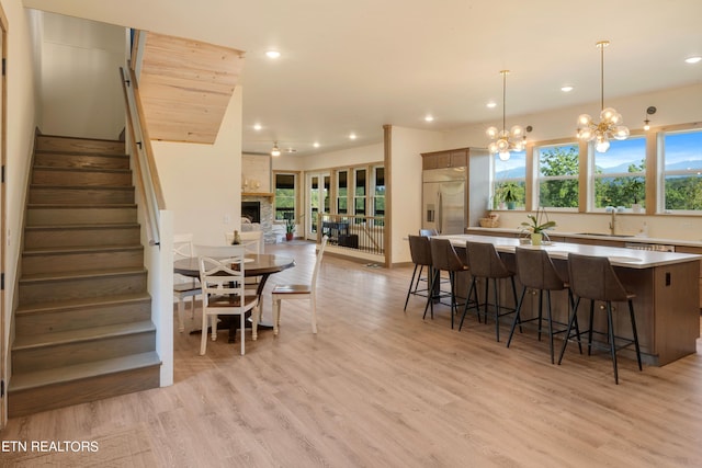 kitchen with stainless steel built in fridge, pendant lighting, sink, light hardwood / wood-style flooring, and a spacious island