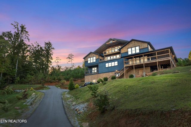 back house at dusk with a deck and a lawn