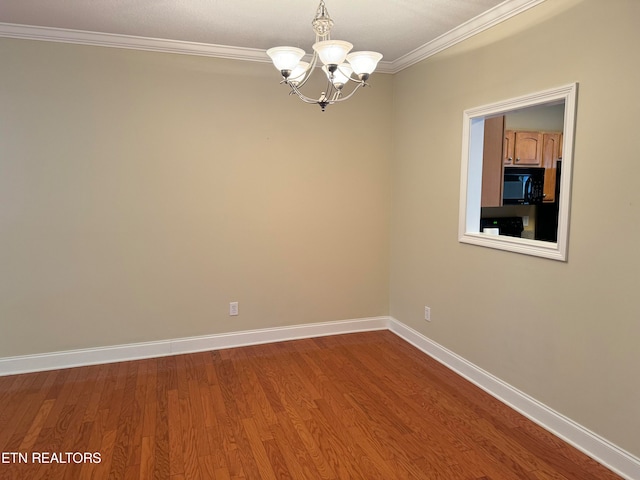 empty room with hardwood / wood-style floors, a chandelier, and ornamental molding