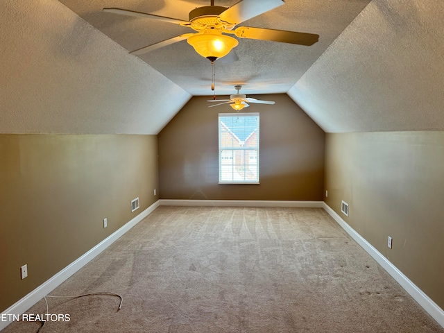 additional living space with light carpet, vaulted ceiling, a textured ceiling, and ceiling fan