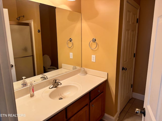 bathroom with vanity, toilet, tile patterned flooring, and a shower with door