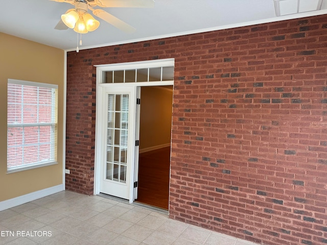 tiled spare room with ceiling fan and brick wall